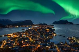 Northern lights over city by the water.