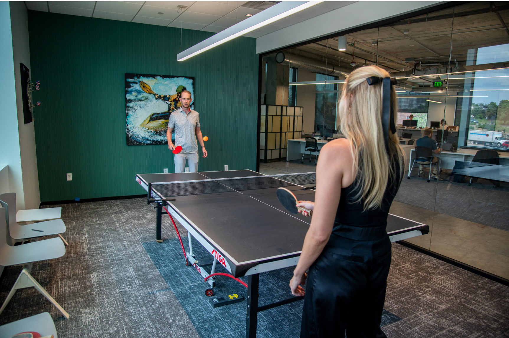 Velocity Global team members playing ping pong in the Badlands game room. 
