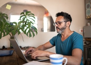 Man with glasses typing on his laptop