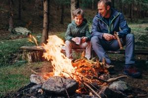 Father and son sitting by the fire at camping site. 