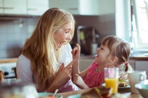 Mother and young daughter laughing and enjoying quality time together in their home kitchen