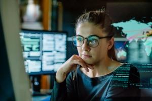 Woman looking at computer with world map graphic in the background