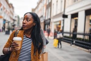 Young employee walks around city in United Kingdom with a coffee