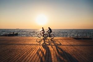 Two bikers take a break after work to bike after work on the boardwalk at sunset.