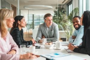 Group of HR leaders discuss the latest industry news around a boardroom table