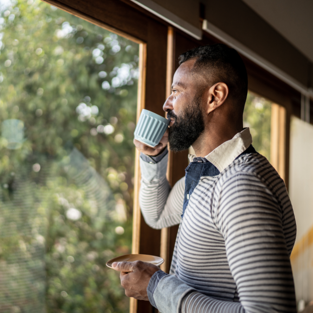 Man sipping coffee while looking out a window
