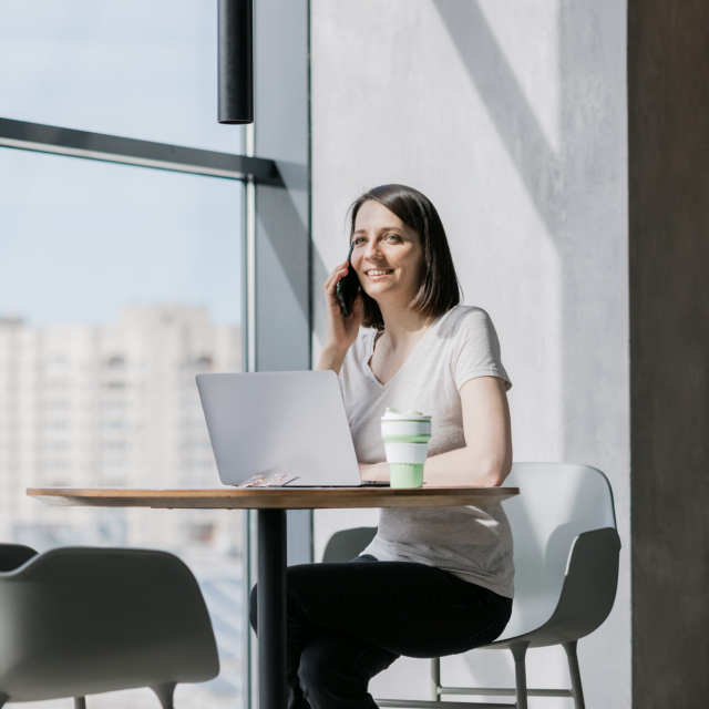 Woman talking on the phone while sitting at a table