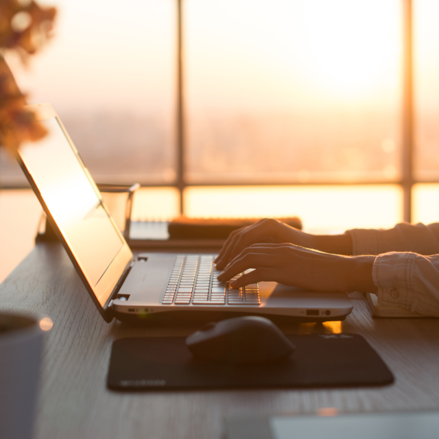 Laptop and mouse on a table with sunset in the background