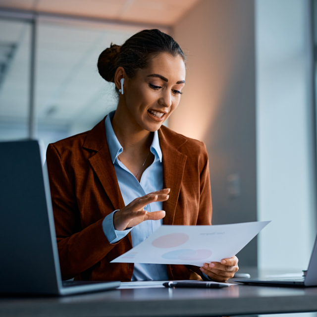 Woman talking through AirPods while looking at a sheet of paper