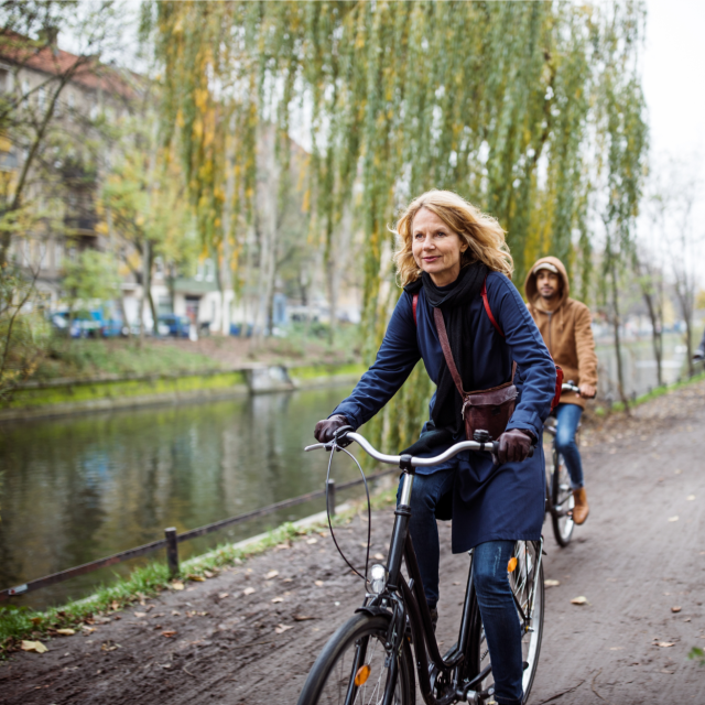 Woman riding bicycle along a river path
