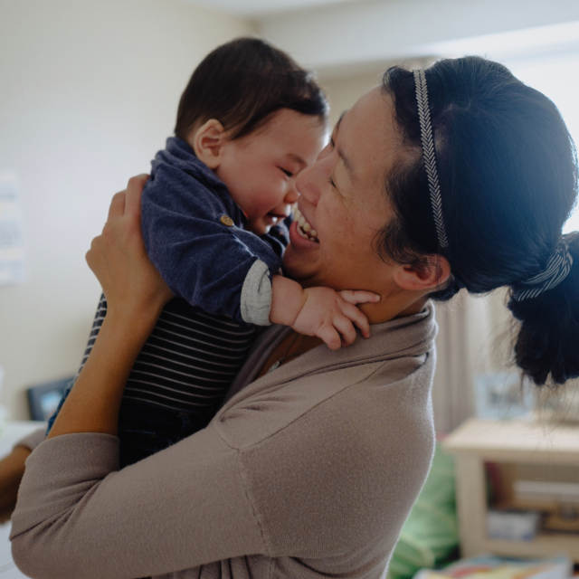 Asian woman holding baby up to her chest