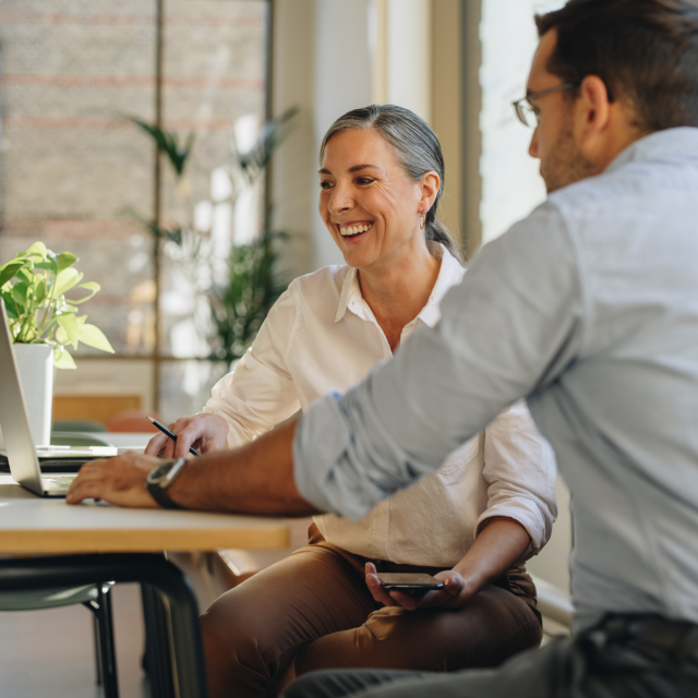 woman and man sitting at table looking at computer