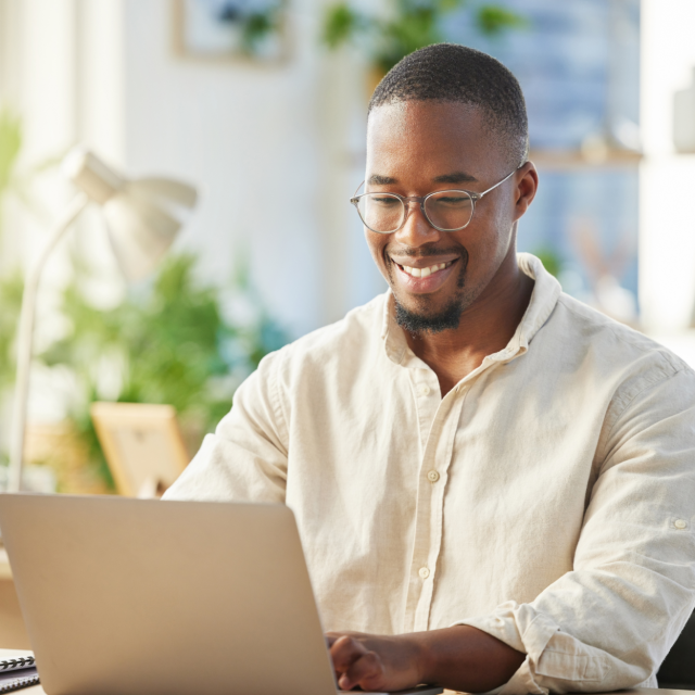 Smiling man using laptop at home