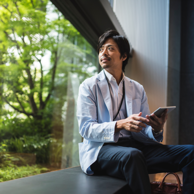 Man on device sitting on window sill looking outside