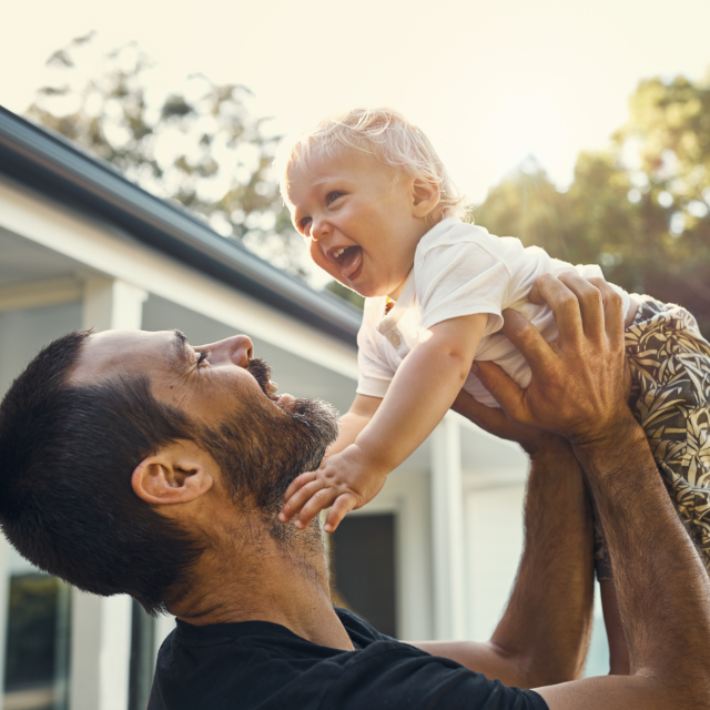 Father enjoying time off from work holding up his child in the air
