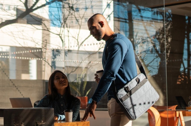 Two remote workers talking at an outdoor café table on the city streets of Brazil