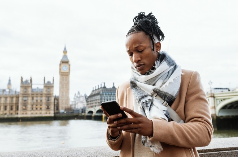 Man working remotely on his smartphone near Big Ben in London, England