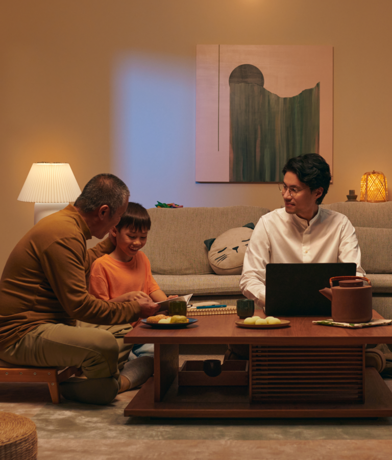 Asian grandfather, father, and son sitting in a living room