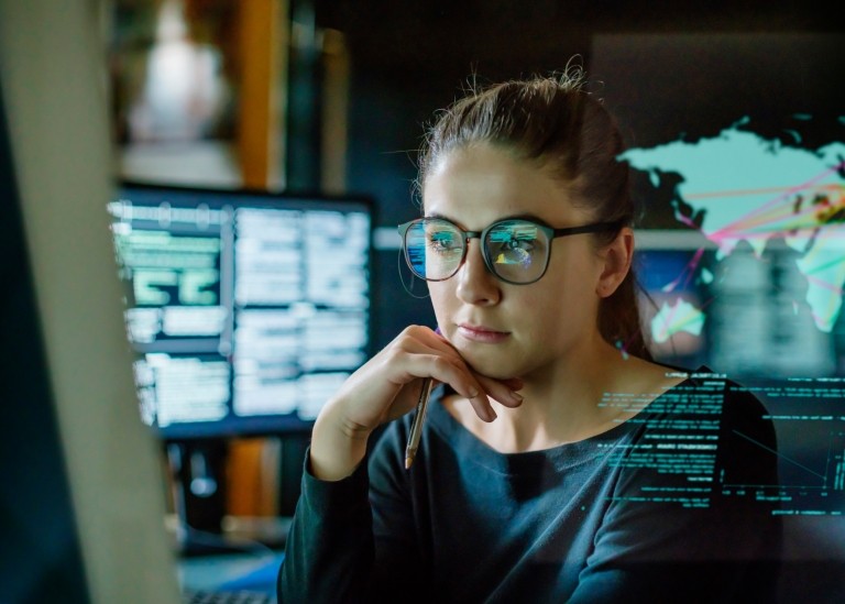 Woman looking at computer with world map graphic in the background