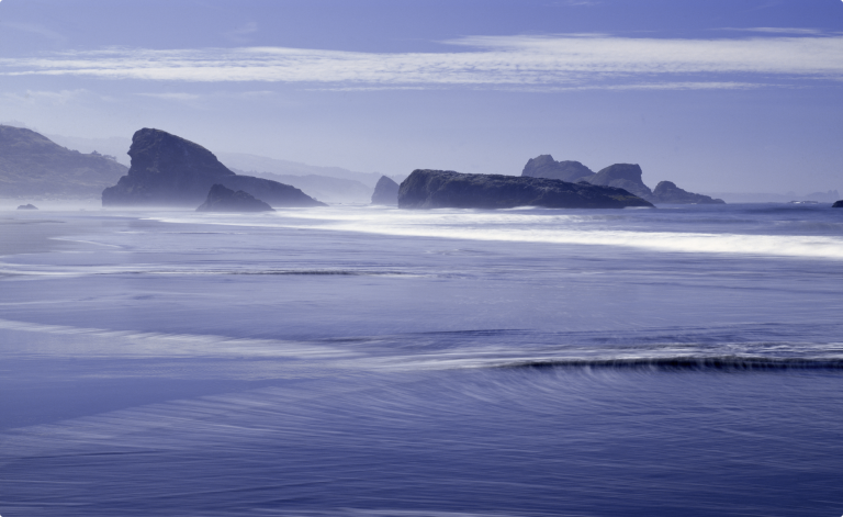 blue ocean with large rocks in background