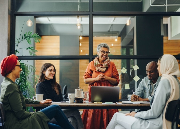 Employees collaborating together around communal table 