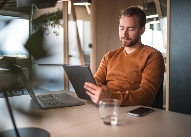 Male HR specialist working on a tablet and researching whether to hire a contractor or employee for a new role