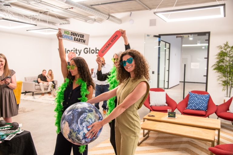 Velocity Global team members pose with photo booth props.