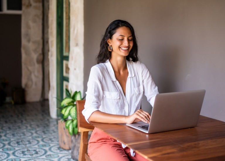 Remote employee in Mexico smiling and working on her laptop