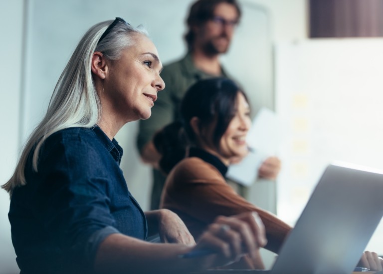 A small human resources team collaborates on work while gathered around a conference room table