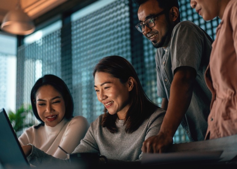 Singapore team gather around laptop to collaborate on project