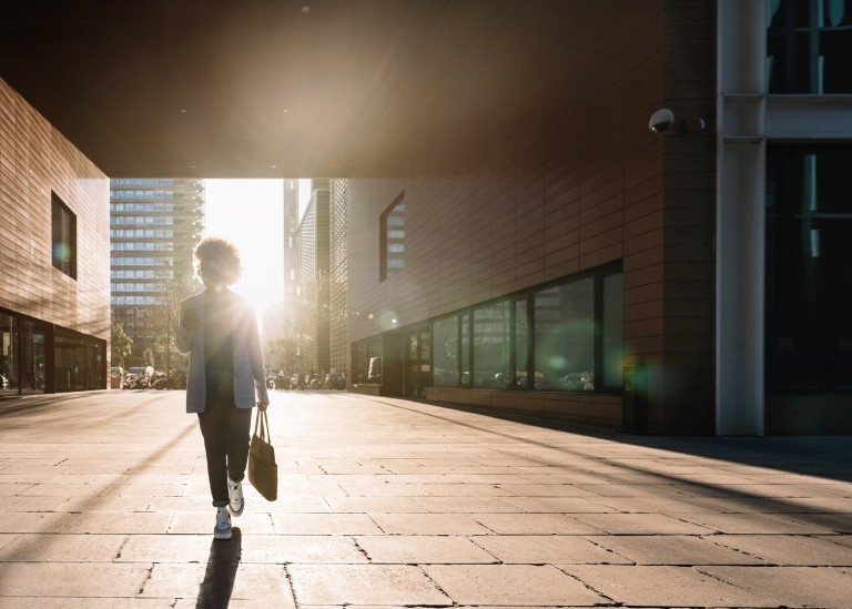 U.S. employee walking through a building underpass on her way to work during daytime.