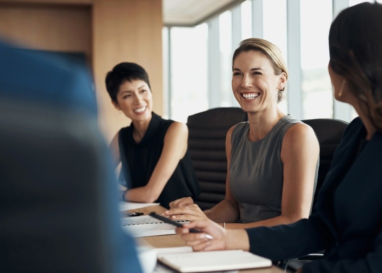 Three executive team members sitting down in conference room discussing new project