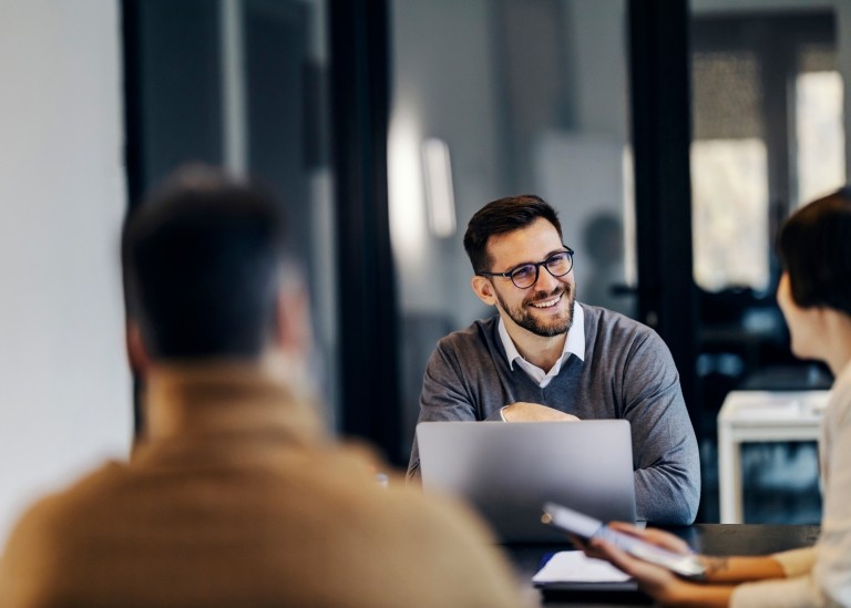 Three business people happily talking and working together inside an office space