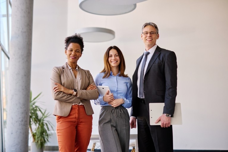 Three coworkers pose for a photo in an office