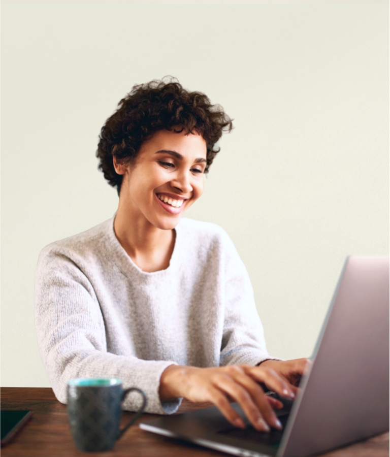 smiling woman at a desk typing on a keyboard