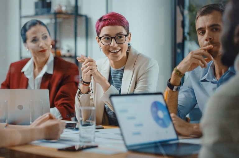 Business men and women sitting around an office table collaborating on a work project.