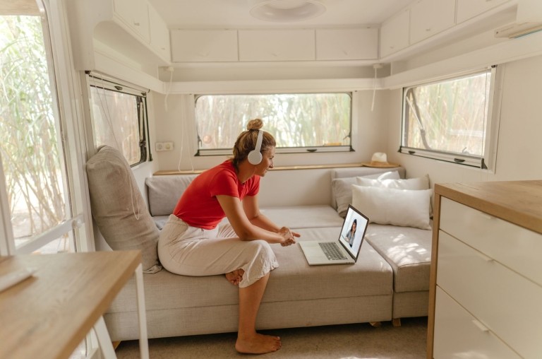 Woman sitting in her RV van with head phones, taking a video call