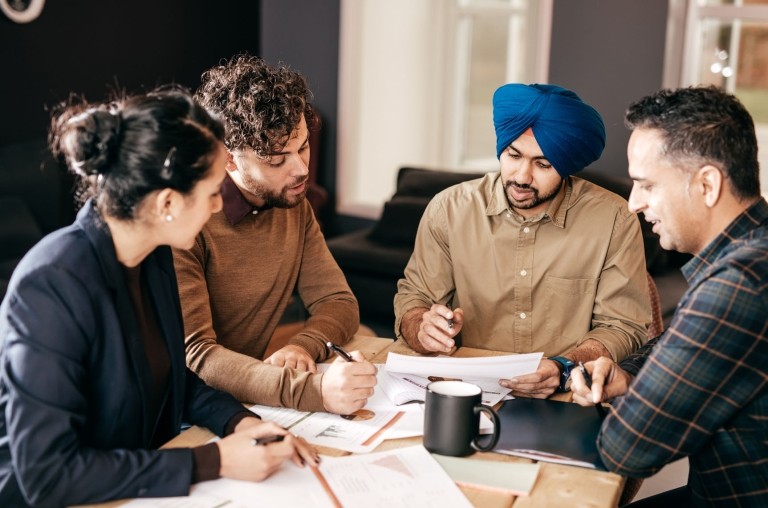 Four people sit around a table discussing business.