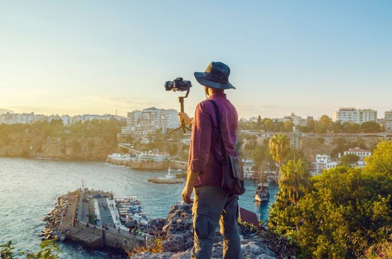 Hero image of a man with camera taking a photo of a coast line