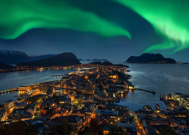 Northern lights over city by the water.