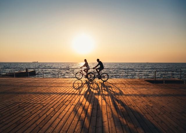 Two bikers take a break after work to bike after work on the boardwalk at sunset.