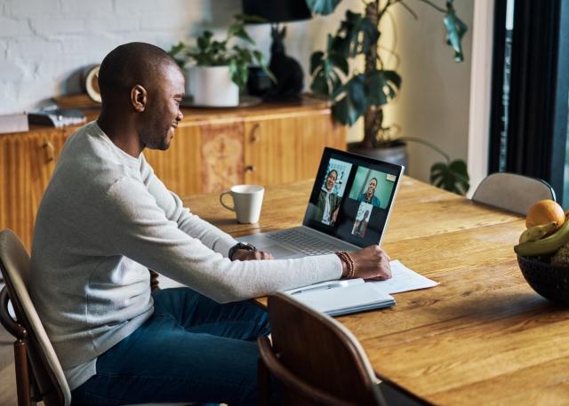 A new employee attends a video onboarding meeting on his laptop while working at home
