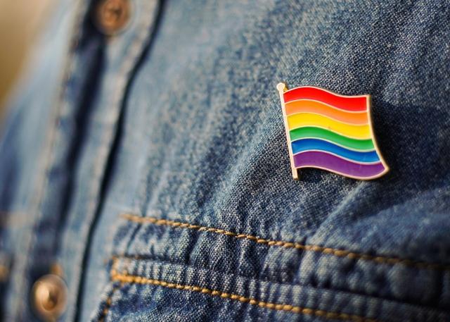 Pride rainbow flag button pinned on denim shirt