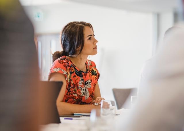 HR professional sitting at a conference table and participating in a discussion about employee’s concerns about a merger.