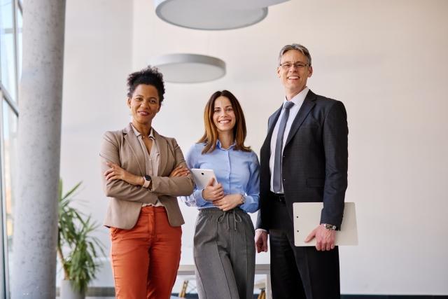 Three coworkers pose for a photo in an office