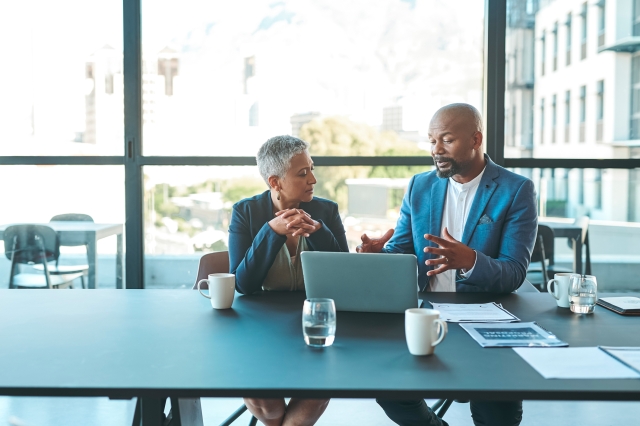 Global payroll managers discussing how currency fluctuations affect payroll