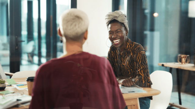 Two women working and smiling at a desk