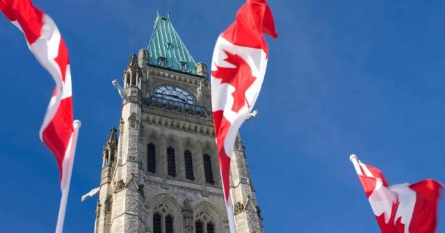three Canadian flags in front of a clock tower