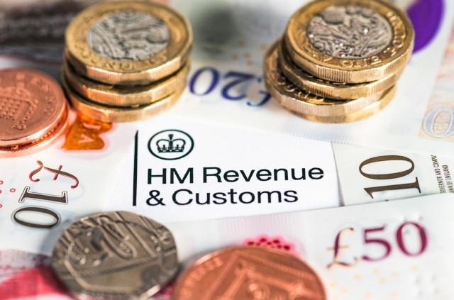 U.K. coins and bills are stacked on top of HMRC paperwork.